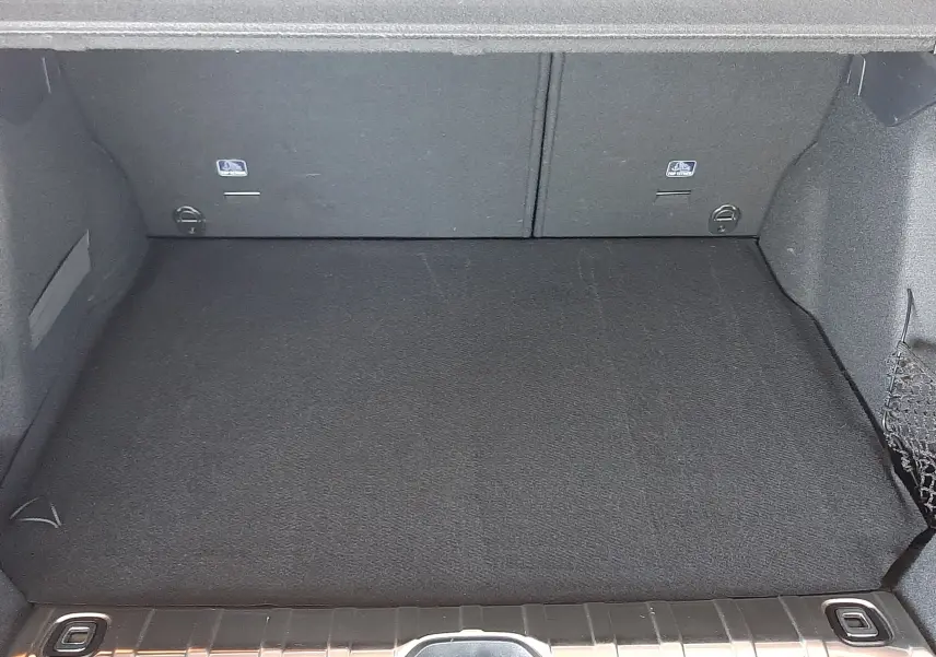 Coffre ouvert vu de l'arrière d'un Peugeot 2008 rouge Ultimate Metal, espace de chargement propre et vide.