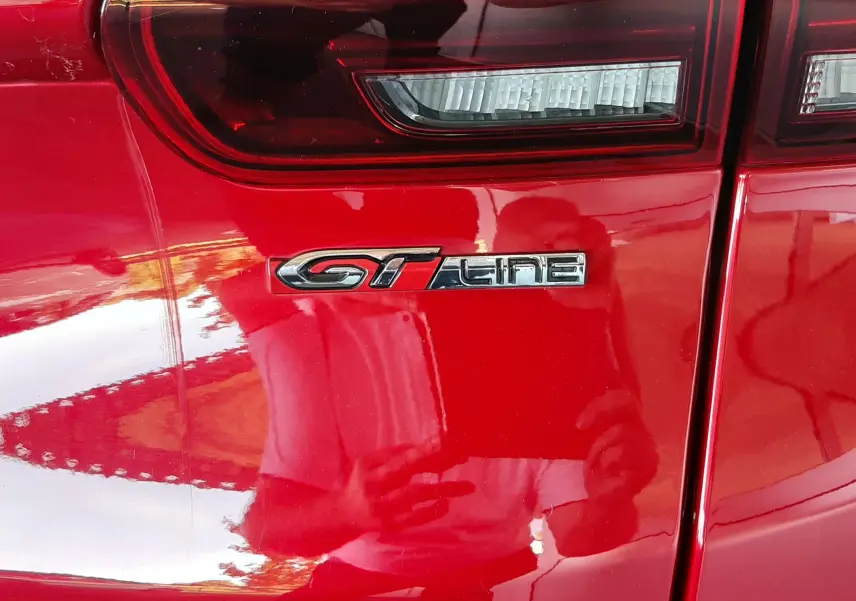 Gros plan sur le feu arrière et l'emblème GT Line du Peugeot 2008 rouge Ultimate Metal côté arrière droit.