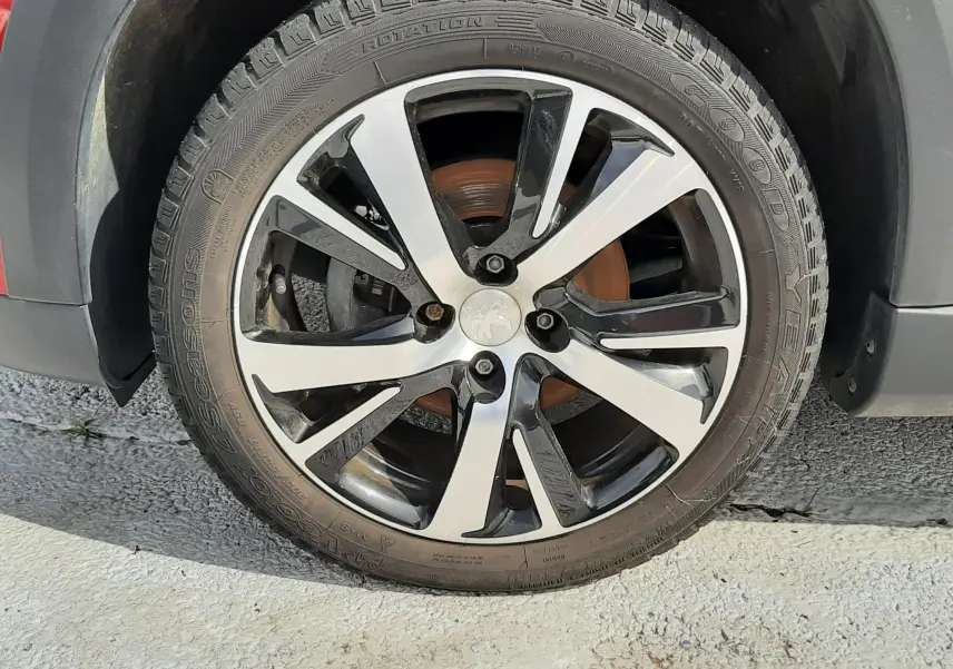 Gros plan sur la roue avant gauche d'un Peugeot 2008 rouge Ultimate Metal avec jante alliage noire et argent.