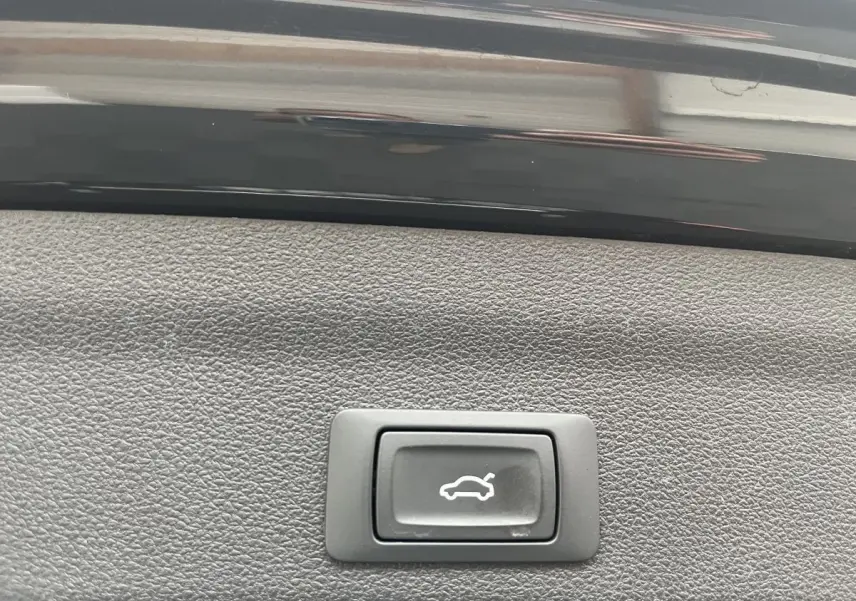 Bouton d'ouverture électrique du coffre sur la garniture intérieure noire d'une Audi A6 40 TDI S Tronic hybrid 2022.