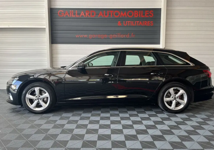 Profil côté gauche d'une Audi A6 noire 2022 garée en intérieur avec jantes alliage et vitres teintées.