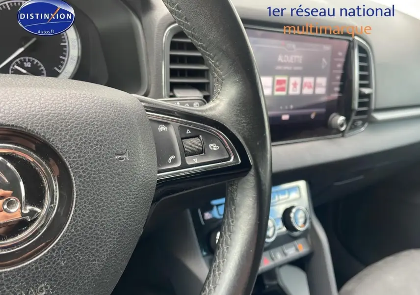 Gros plan sur le volant cuir multifonction et l'écran tactile du tableau de bord intérieur d'une Skoda Karoq noire 2018.