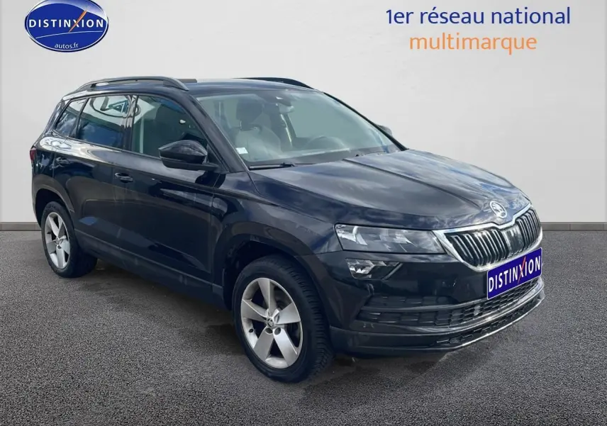 Vue 3/4 avant droite d'un Skoda Karoq noir 2018 avec jantes alu et barres de toit visibles.