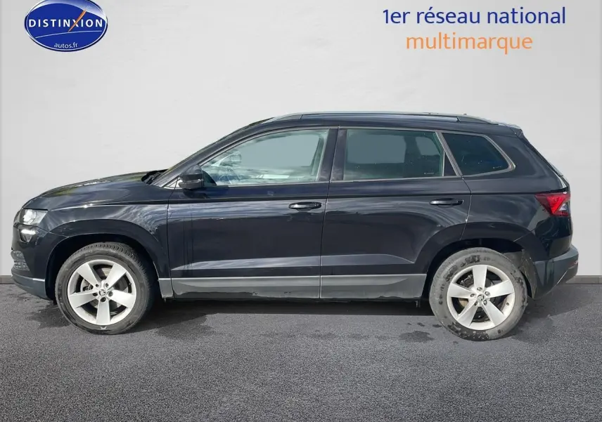 Profil côté gauche d'un Skoda Karoq noir 2018 avec jantes alu et barres de toit visibles sur fond clair.