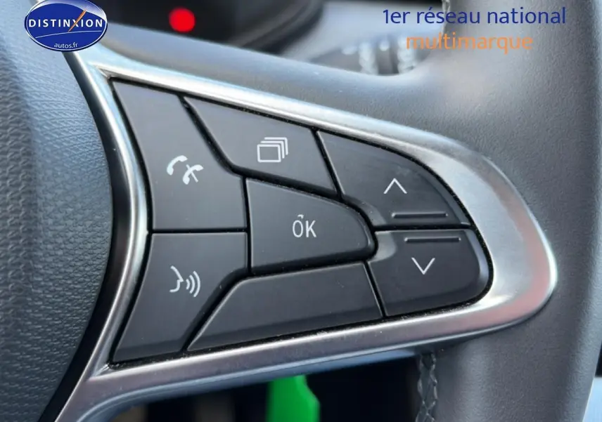 Gros plan sur les commandes multifonctions noires du volant d'une Renault Clio V gris foncé, version 2025.