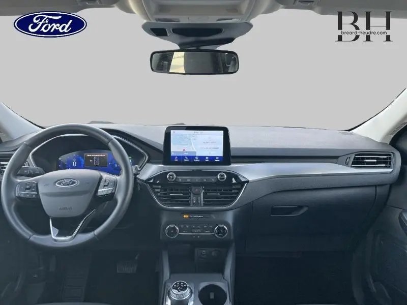 Vue intérieure avant du Ford Kuga 2023 avec tableau de bord noir, écran tactile central et volant cuir multifonction.