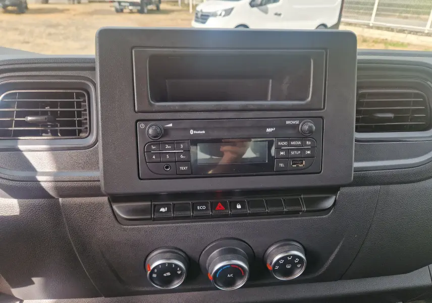 Tableau de bord noir du Renault Master Châssis Cabine 2024, vue frontale centrée sur la radio et les commandes de climatisation.