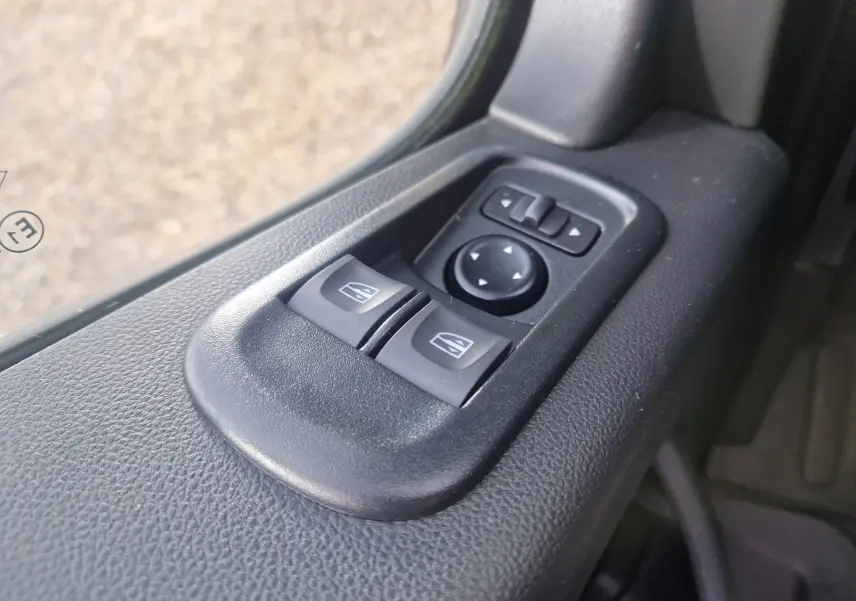 Gros plan sur les commandes électriques des vitres et des rétroviseurs côté conducteur du Renault Master Châssis Cabine blanc.