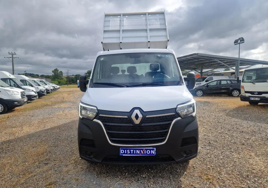 Vue avant d’un Renault Master Châssis Cabine blanc avec benne relevée sur un terrain extérieur sous ciel nuageux.