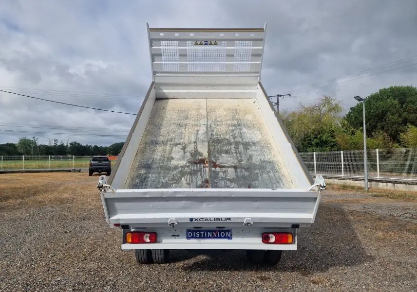 Vue arrière d'une benne blanche Renault Master Châssis Cabine 2024 relevée, avec plateau métallique usé et roues jumelées visibles.