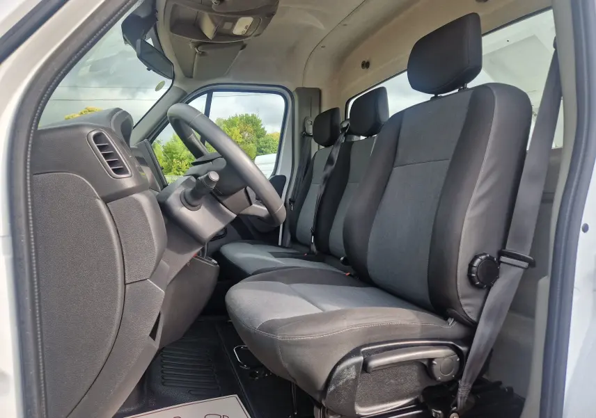 Vue intérieure côté conducteur du Renault Master Châssis Cabine blanc 2024, montrant les sièges tissu gris et noir et le volant.