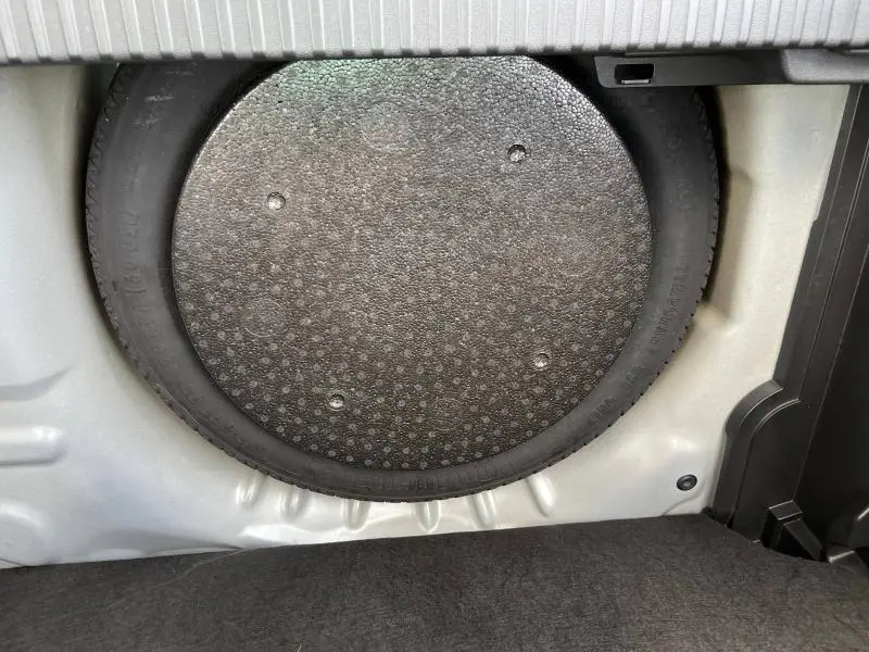 Gros plan sur la roue de secours dans le coffre d'une Citroën C3 Aircross gris acier, montrant le rangement intérieur.