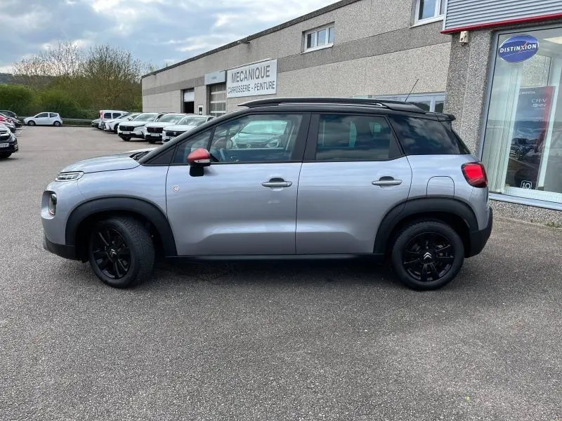 Profil droit d'un Citroën C3 Aircross 2020 gris acier avec toit noir et coques de rétroviseurs rouges.
