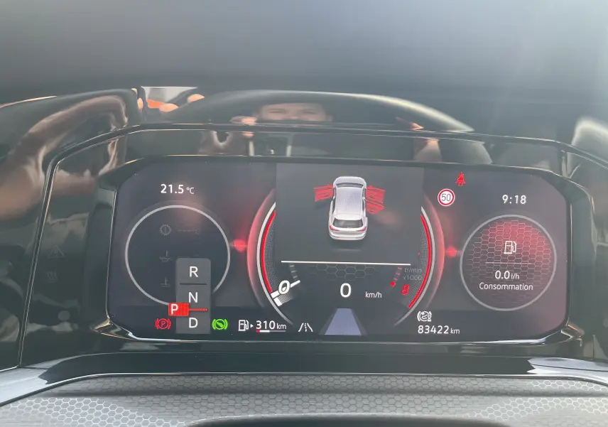 Tableau de bord numérique de la Volkswagen Golf VIII GTI gris, affichant la vitesse à 0 km/h et les portes ouvertes.