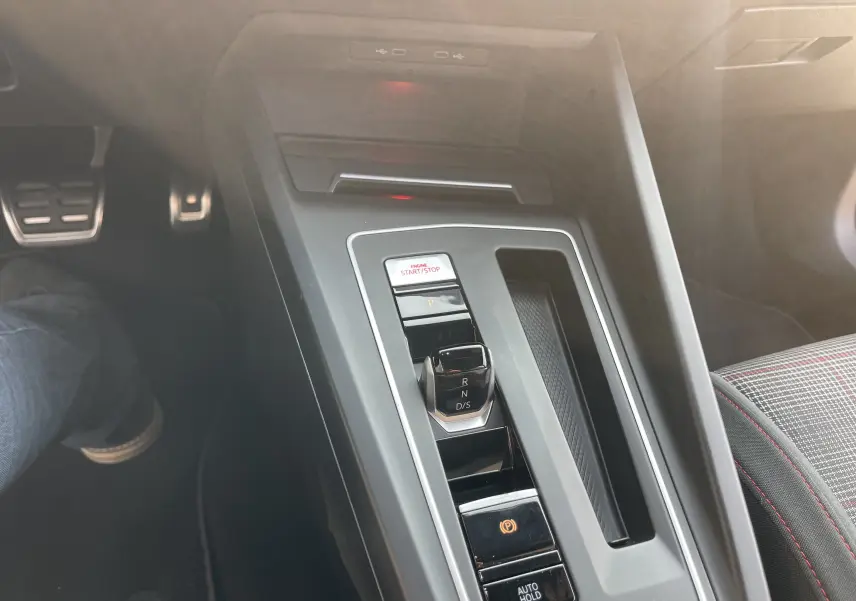 Vue rapprochée de la console centrale de la Volkswagen Golf VIII GTI 2021 avec levier de vitesse DSG et siège tissu à surpiqûres rouges.