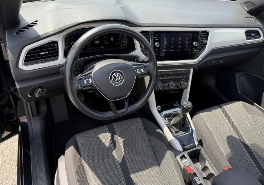 Vue intérieure avant du Volkswagen T-Roc Cabriolet 2021 avec tableau de bord numérique et volant cuir multifonction.