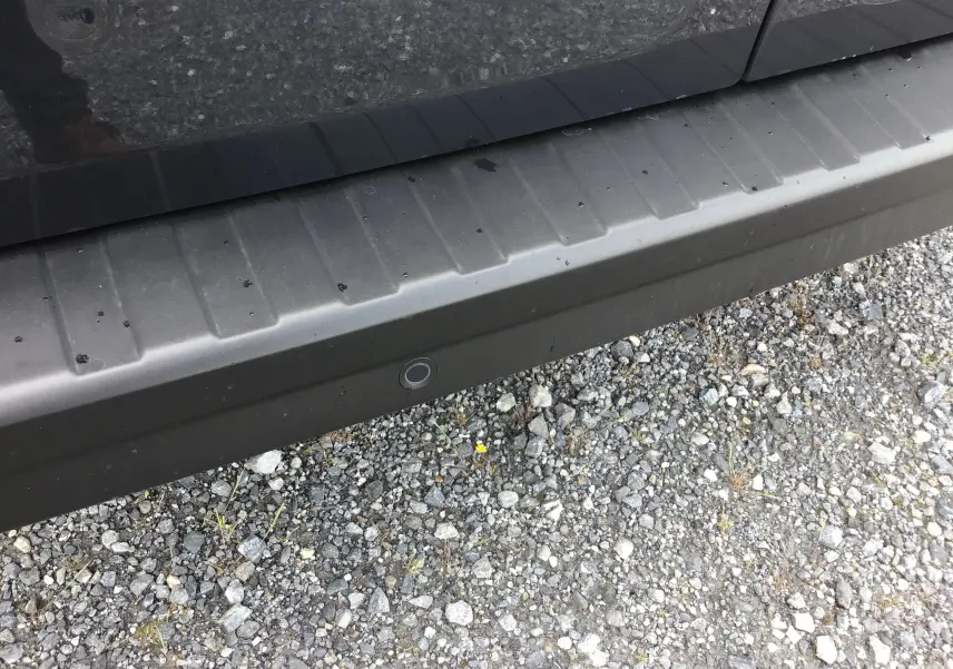 Gros plan sur le bas de porte gris comète du Renault Trafic Fourgon, avec capteur de recul visible sur le pare-chocs.