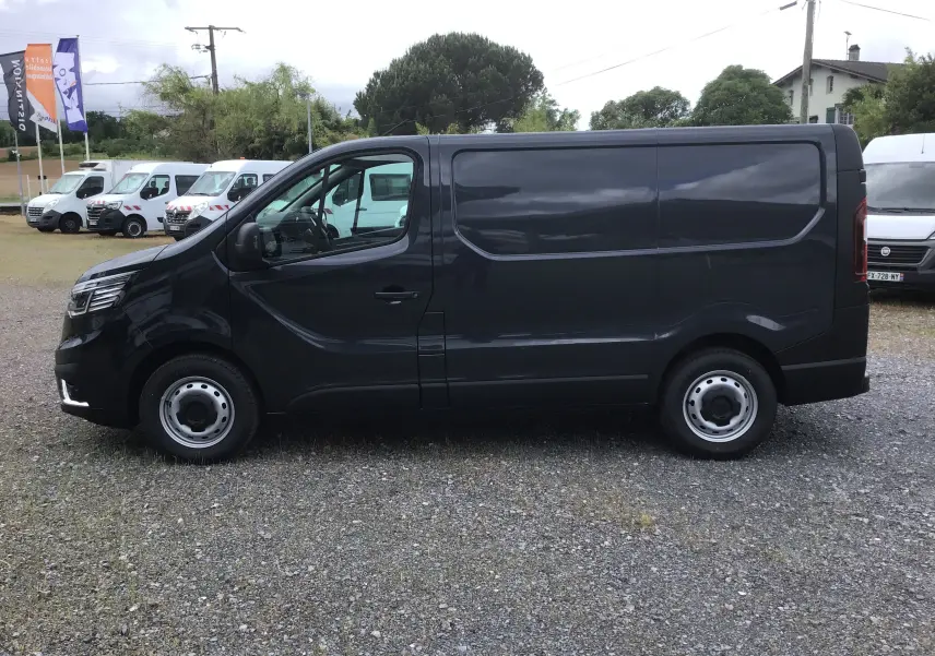 Vue de profil côté gauche d’un Renault Trafic Fourgon gris comète 2025, avec carrosserie lisse et jantes acier.