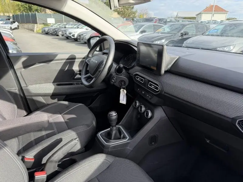 Vue intérieure côté conducteur du Dacia Jogger 2025, montrant le volant, la console centrale avec boîte manuelle et l’écran tactile.