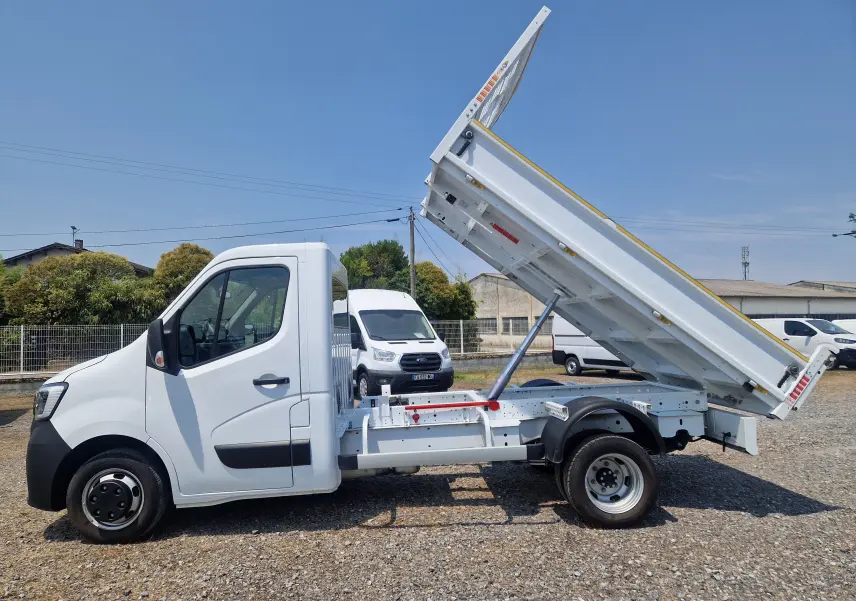 Vue latérale gauche d’un Renault Master Châssis Cabine blanc 2024 avec benne basculante relevée et roues jumelées arrière.
