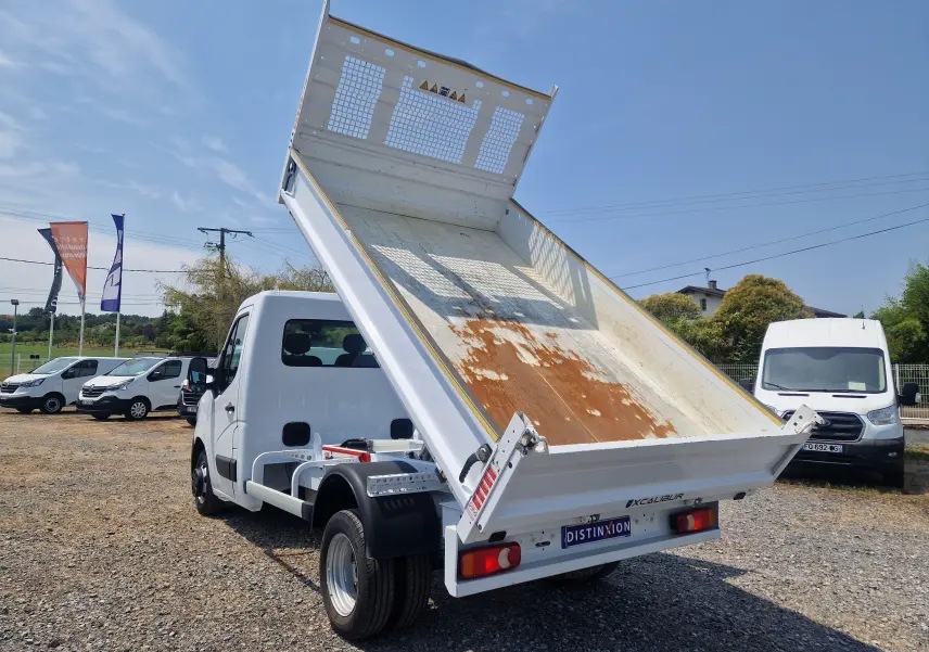 Vue 3/4 arrière droite du Renault Master Châssis Cabine blanc avec benne relevée et roues jumelées, sur parking extérieur.