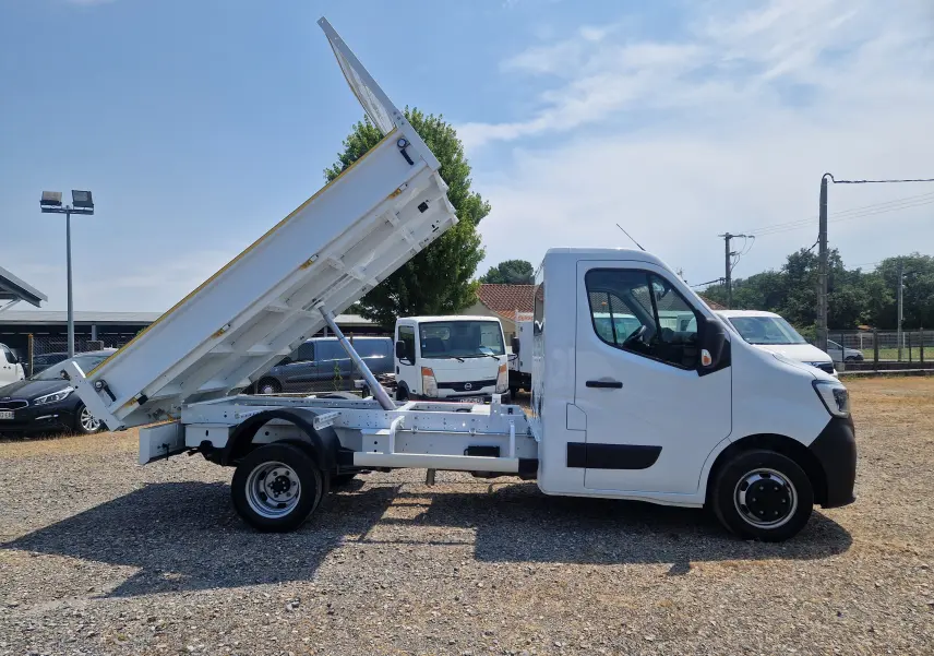 Vue latérale droite d’un Renault Master Châssis Cabine blanc avec benne relevée, roues jumelées et cabine simple.