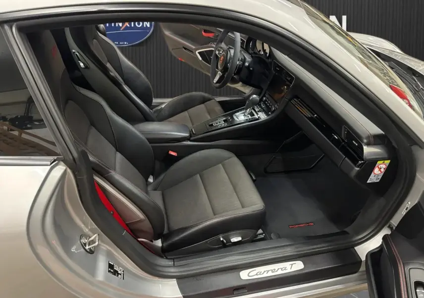 Vue intérieure côté conducteur de la Porsche 911 991 2 Carrera T gris GT Silver avec sièges sport noirs et volant alcantara.