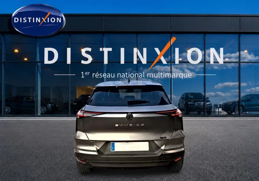 Vue arrière d'une Renault Symbioz gris cassiope garée devant une vitrine avec logo Distinxion.
