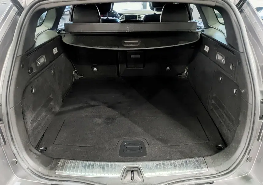 Coffre ouvert d'une Renault Talisman Estate gris Cassiopé, montrant l'espace de chargement intérieur noir et la plage arrière.