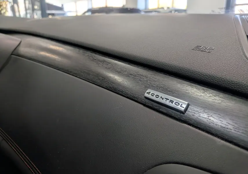 Gros plan sur la planche de bord noire avec insert bois et logo 4CONTROL dans une Renault Talisman Estate 2022.