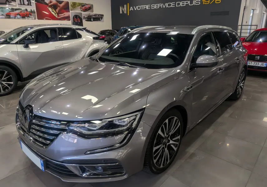 Renault Talisman Estate gris Cassiopé en 3/4 avant droit, avec jantes alliage et calandre chromée brillante.