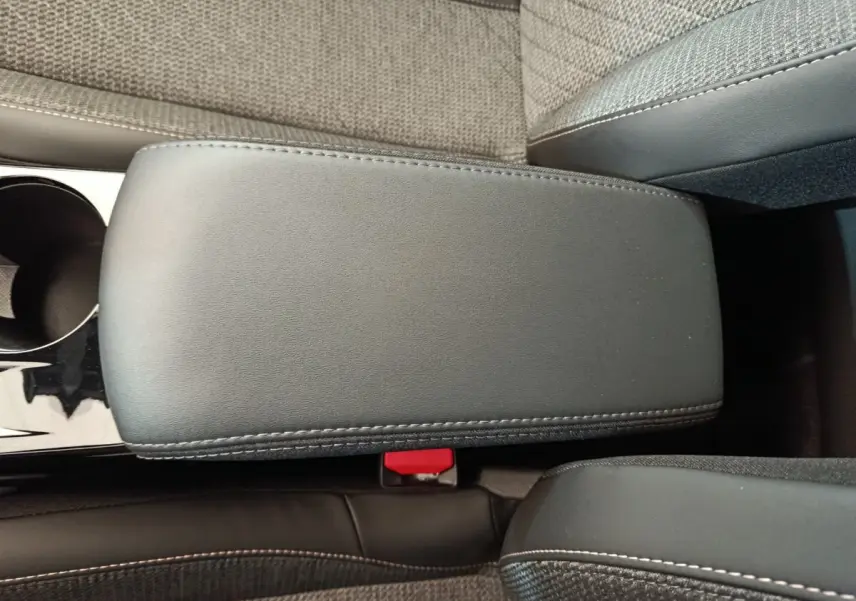 Détail de l'accoudoir central noir avec surpiqûres blanches et siège tissu gris clair dans une Peugeot 208 2025.