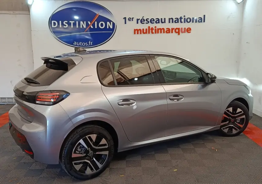 Vue 3/4 arrière droite d'une Peugeot 208 PureTech 100 S&S Allure gris clair avec jantes noires et phares LED.