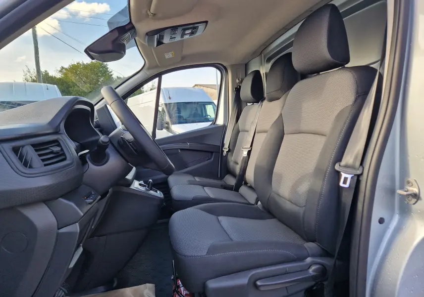 Vue intérieure côté conducteur du Renault Trafic Fourgon gris Highland 2025, montrant les sièges avant et le tableau de bord.