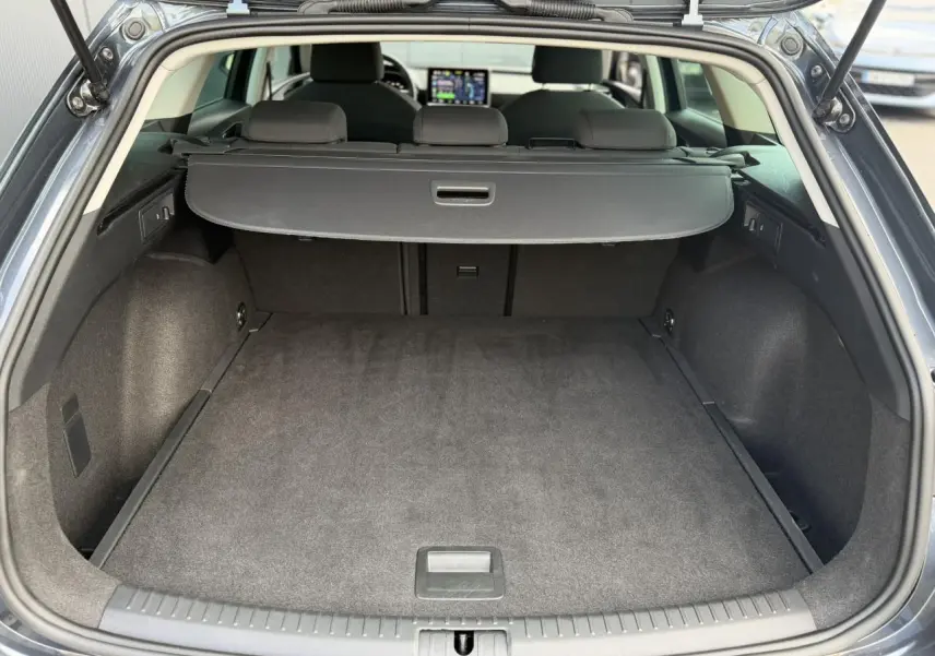 Coffre ouvert vu de l'arrière d'une SEAT LEON ST gris magnétique, avec cache-bagages et intérieur noir.