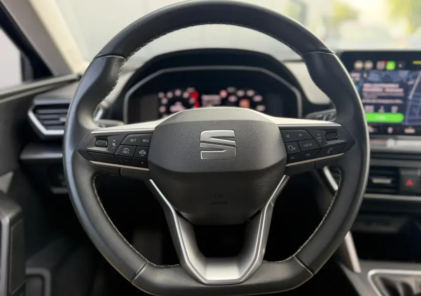 Volant cuir multifonction noir de la SEAT LEON ST 2025, vue frontale centrée sur les commandes intégrées.