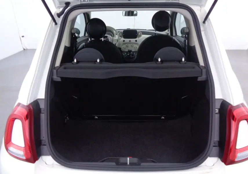 Vue arrière ouverte du coffre d'une FIAT 500 blanche Gelato, montrant l'intérieur noir et les sièges avant.