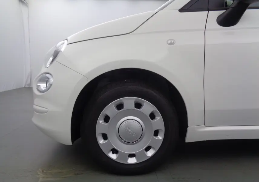 Gros plan sur la roue avant gauche d'une FIAT 500 blanche Gelato, mettant en valeur la jante et le phare rond avant.