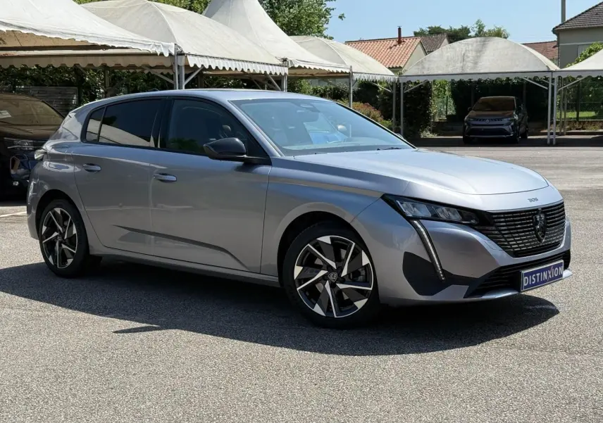 Peugeot 308 gris Artense vue 3/4 avant droit, avec jantes alliage et calandre noire distinctive.