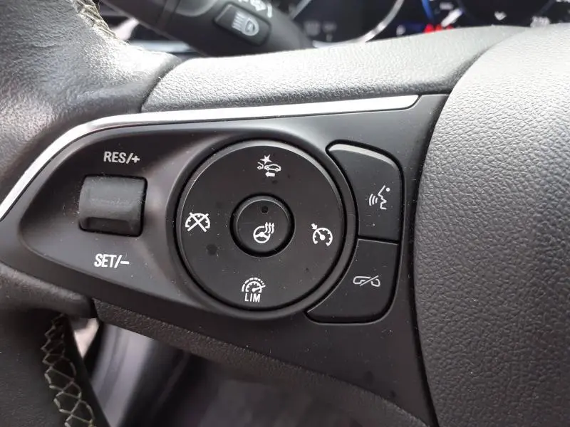 Gros plan sur les commandes au volant gauche de l'Opel Insignia Grand Sport 2021, boutons de régulateur de vitesse et assistance.