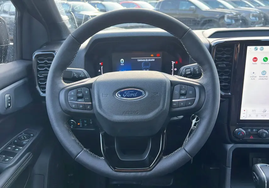 Vue frontale du volant et tableau de bord du Ford Ranger 2025 noir shadow avec écran tactile central et commandes au volant.