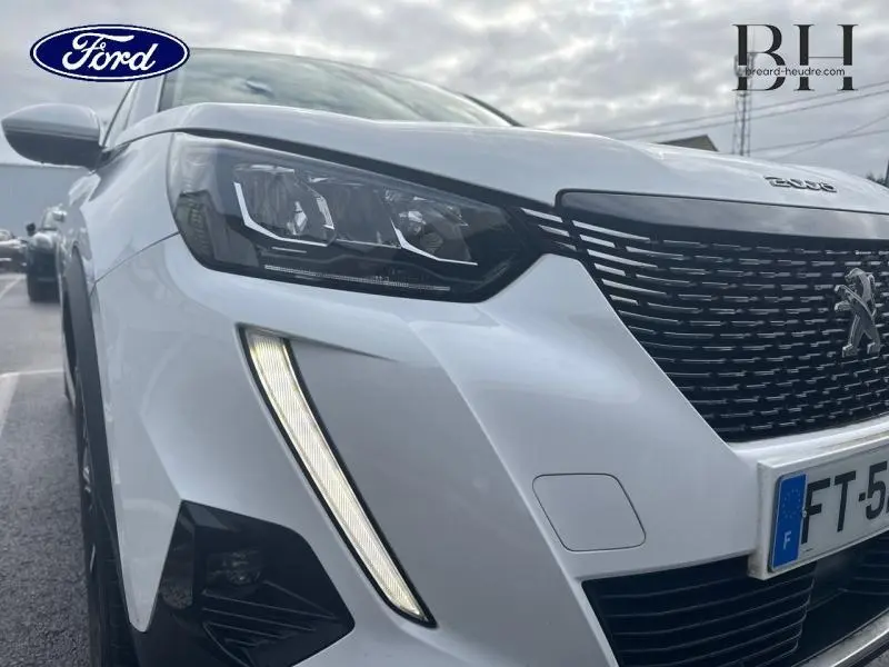 Gros plan sur l'avant droit d'un Peugeot 2008 blanc banquise avec phares LED et calandre noire.