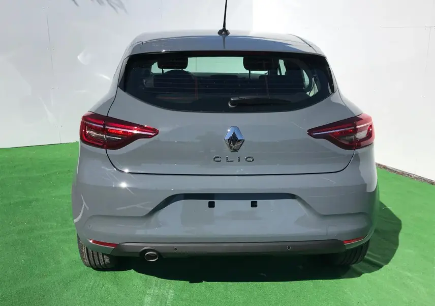 Vue arrière d'une Renault Clio 2021 gris Urban avec feux LED et échappement visible sur fond vert.