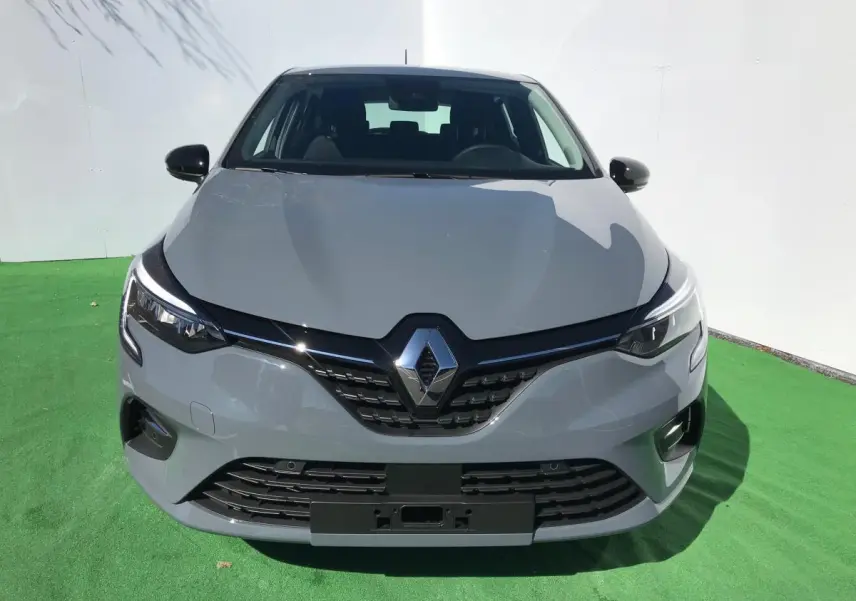 Vue avant d'une Renault Clio gris Urban 2021 avec phares LED et calandre noire brillante sur fond vert.