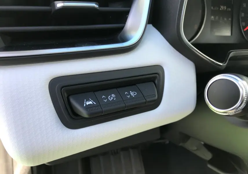 Gros plan sur les commandes d'assistance à la conduite sur tableau de bord blanc de la Renault Clio 2021 Gris Urban.