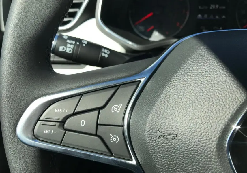 Gros plan sur le volant multifonctions en cuir noir de la Renault Clio Gris Urban, avec commandes de régulateur de vitesse.