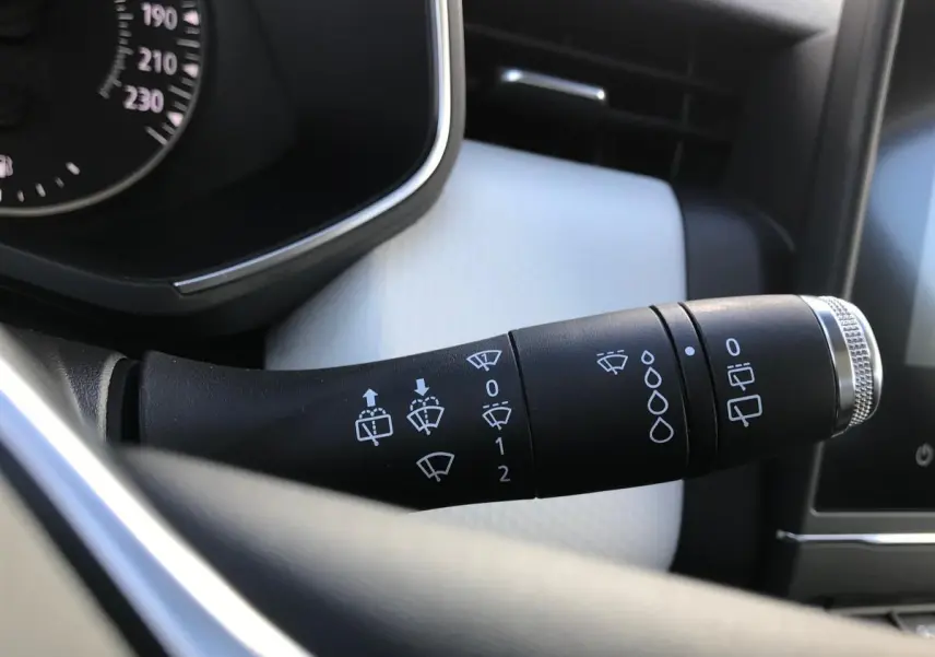 Gros plan sur la commande d'essuie-glaces à gauche du volant dans l'habitacle clair de la Renault Clio Gris Urban 2021.