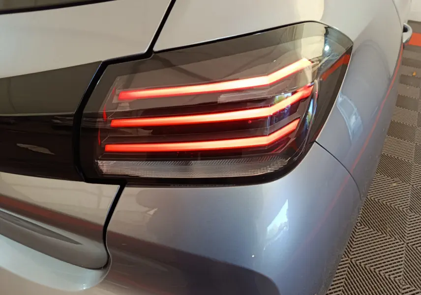 Gros plan sur le feu arrière droit allumé d'une Peugeot 208 PureTech 100 S&S Allure gris clair, vue arrière.