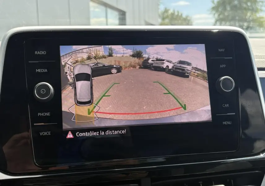 Écran tactile intérieur montrant la caméra de recul du Volkswagen T-Roc gris pyrite avec lignes de guidage vertes et rouges.