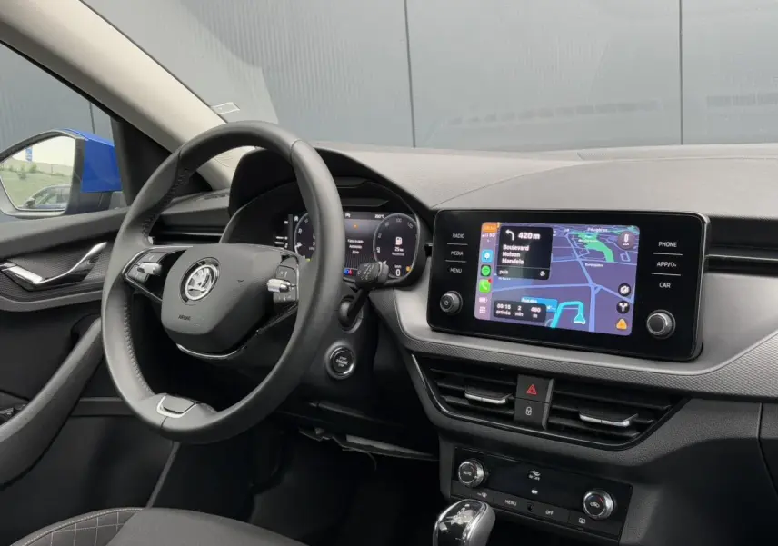 Intérieur de la Skoda Scala bleu Energy, vue côté conducteur sur le volant cuir et l’écran tactile de navigation.
